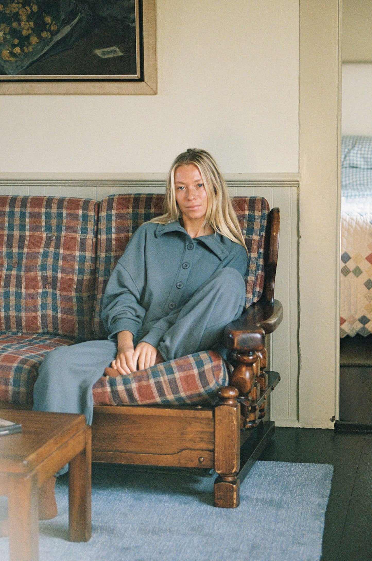 Woman sitting on a plaid couch in a cozy living room.